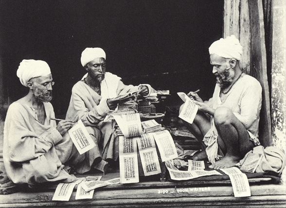 Three men sitting around a pile of manuscripts.