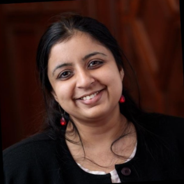 Supurna Dasgupta smiling with a wood panel backdrop